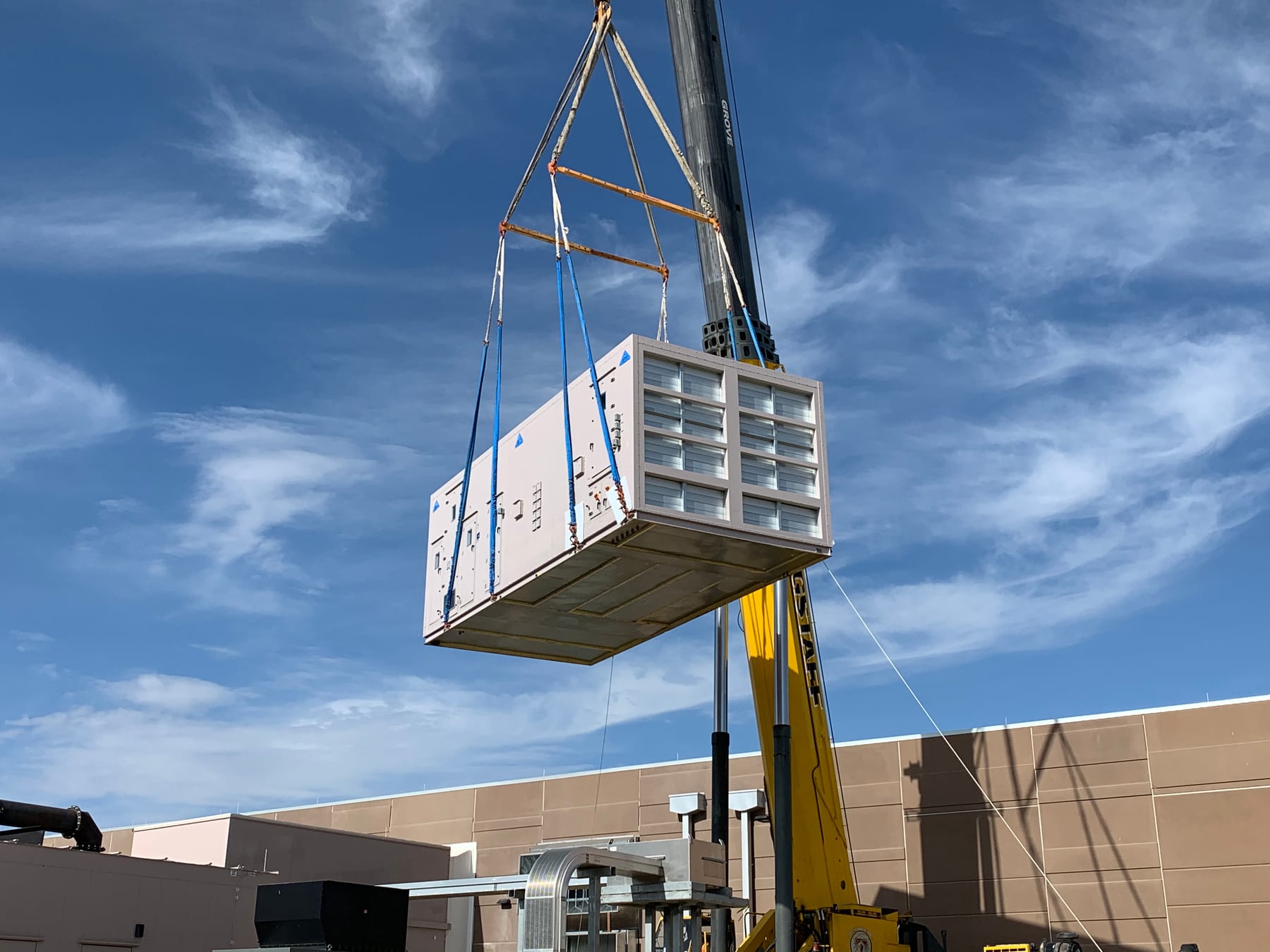 Cooling module on a crane lift toward a rooftop.